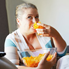 The fat woman is eating chips