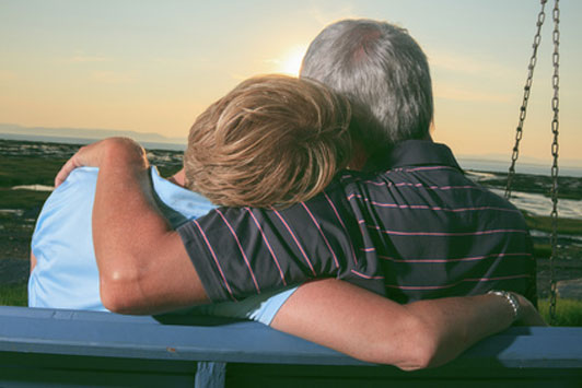 couple with age gap on bench watching sunset