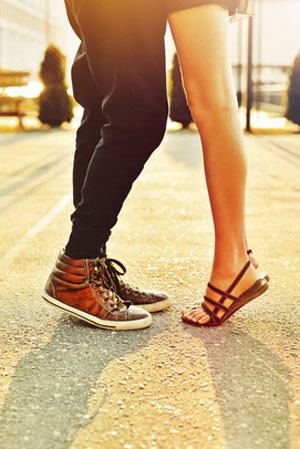 couple with feet facing each other and woman on tip toes