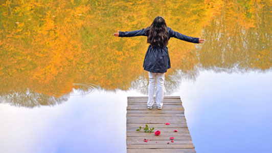 woman standing at end of path of rose petals