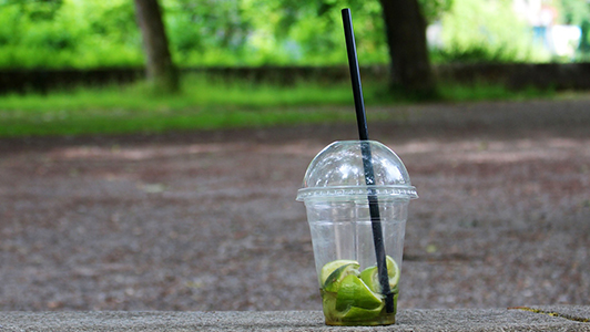 Transparent plastic cup with sliced lime in it.