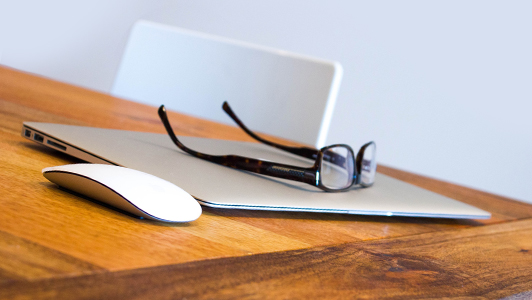 Closed laptop, glasses and a mouse.