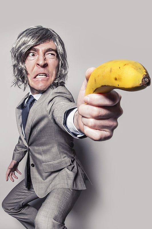 A guy with silver wig holding a banana.