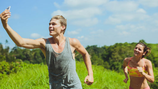 man taking selfie while being chased by woman from behind