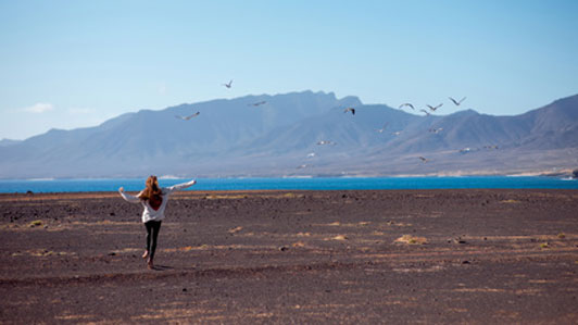 woman in good mood running forward towards beach