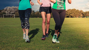 three friends in the middle of a field jogging together