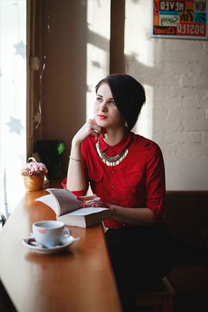 woman in cafe reading book looking out window