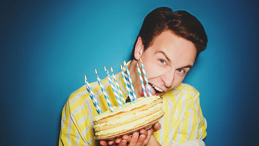 guy gnawing at cake with candles