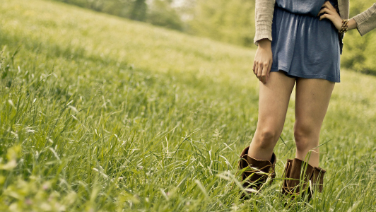 Girl in short dress standing in the meadow.