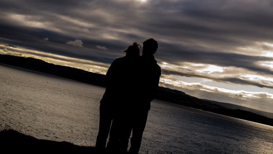 Couple standing near a lake.