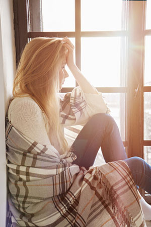 woman sitting alone near window thinking