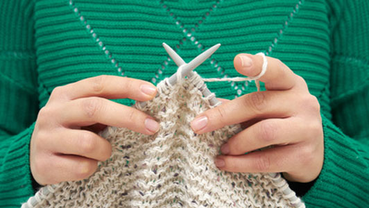 woman in green sweater kniting