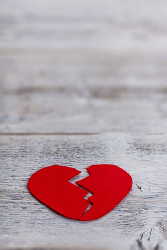 red broken heart on wooden surface