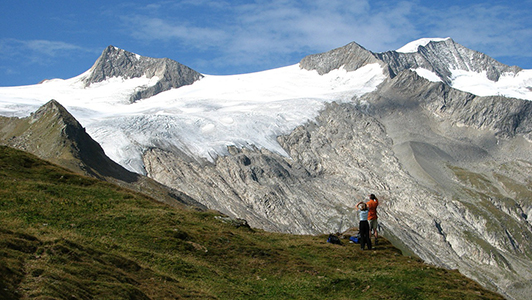 A couple on a mountain looking at snow.