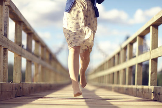 girl running over bridge barefoot