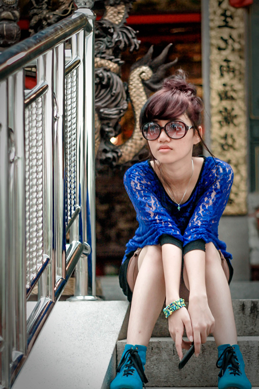 Girl with glasses sitting on stairs.