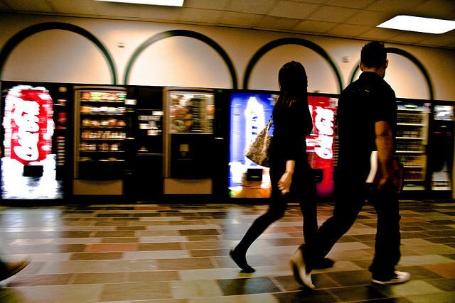 two students walking by vending machine between classes