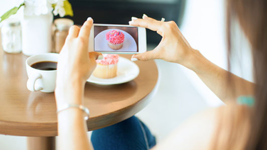 girl taking picture of cupcake