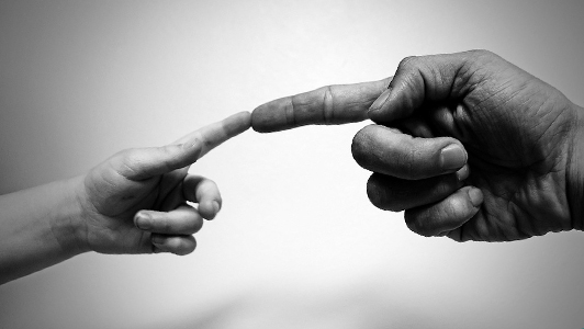 A finger of a child touching a finger of a grown man