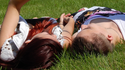 A couple lying on grass.