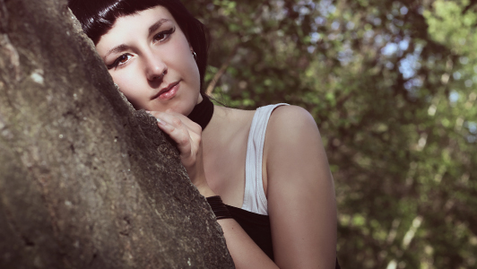 Pale girl leaned on a tree.