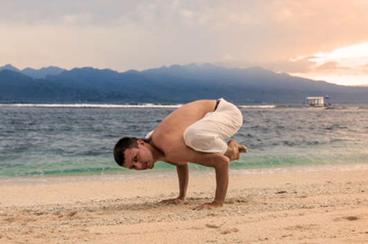 guy in full yoga pose on beach