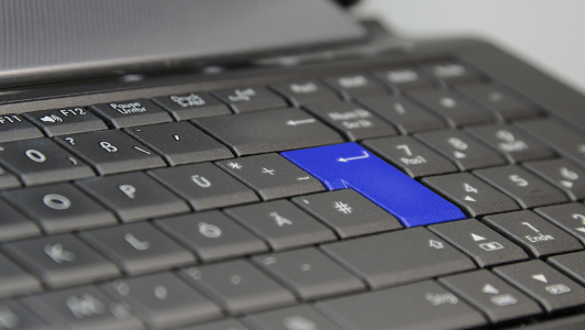 Laptop keyboard with a blue enter button.