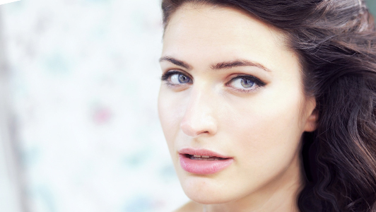 Portrait of a young woman with blue eyes and wavy hair.