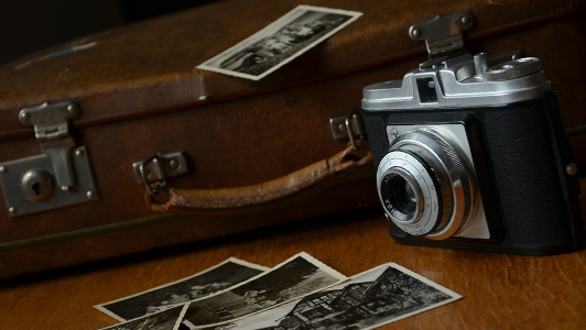 Old suitcase, camera and black and white photos.