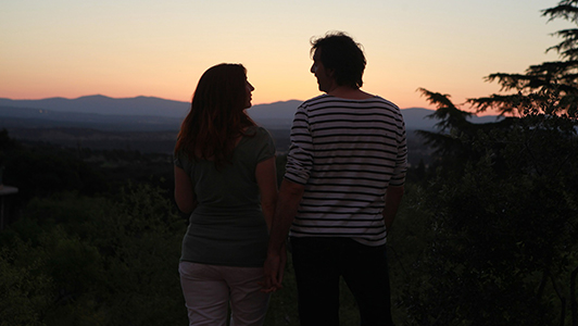 Couple holding hands and looking at each other in sunset.