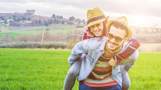 young woman getting piggy back ride from boyfriend