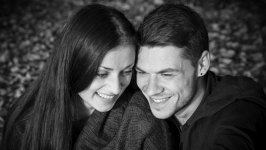 black and white image of smiling couple sitting in park