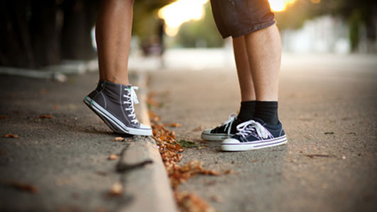 legs of young woman standing in front of guy on tippy toes