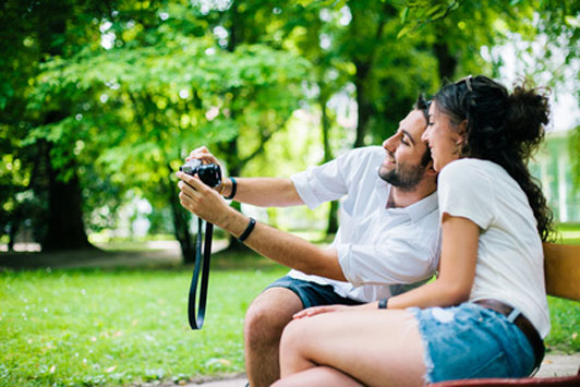 couple taking picture outdoors on park bench