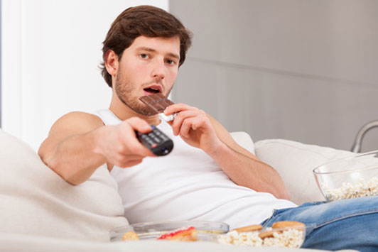 guy watching tv about to eat chocolate