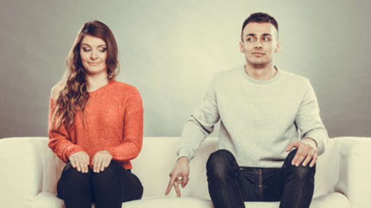 Shy woman and man sitting on sofa