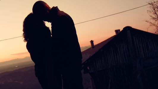 A couple standing close to each other in sunset