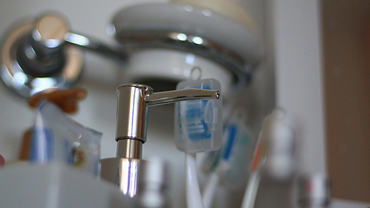 A modern silver faucet and tooth brushes