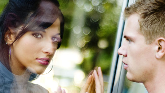 man and women looking at each other through glass