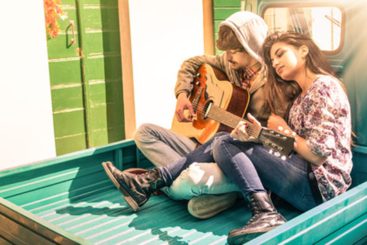 couple on flatbed of truck playing music