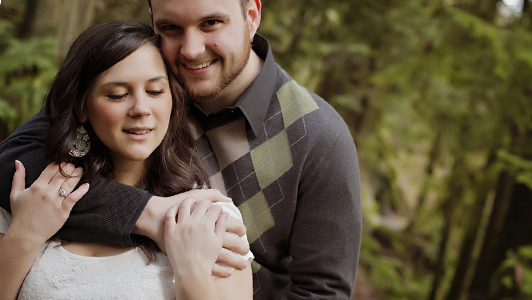 Guy in a sweater hugging a girl in a white shirt.