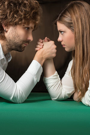 woman faces man in arm wrestling match