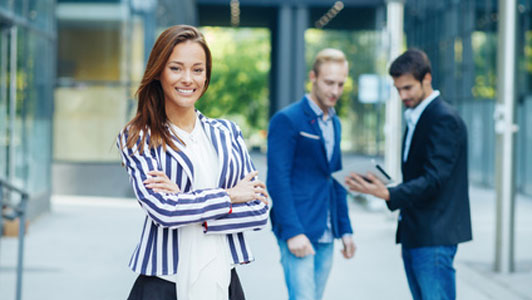 dressed up office woman standing in front of two guys talking