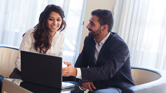 man and woman in chairs sitting in talking front of laptop