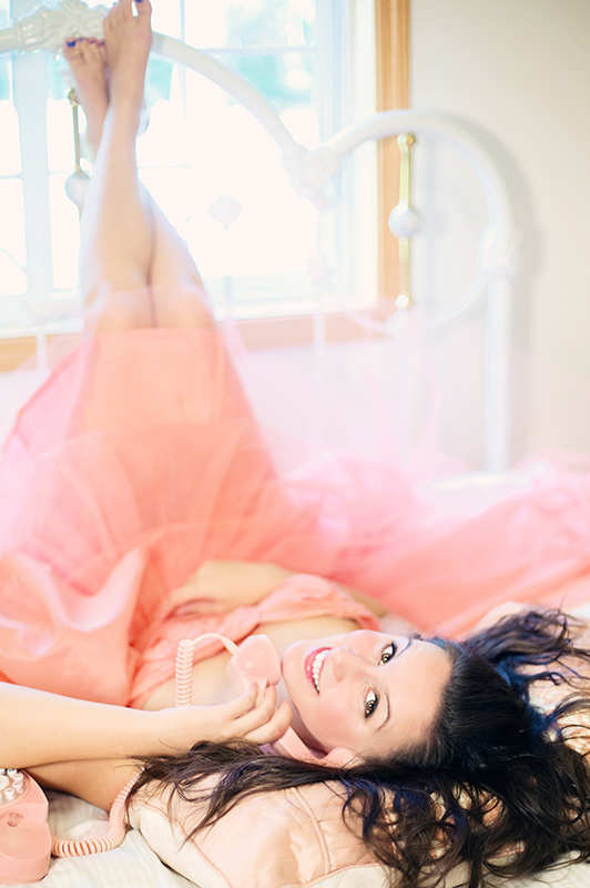 Girl in a pink tutu lying on a bed and talking on the phone.