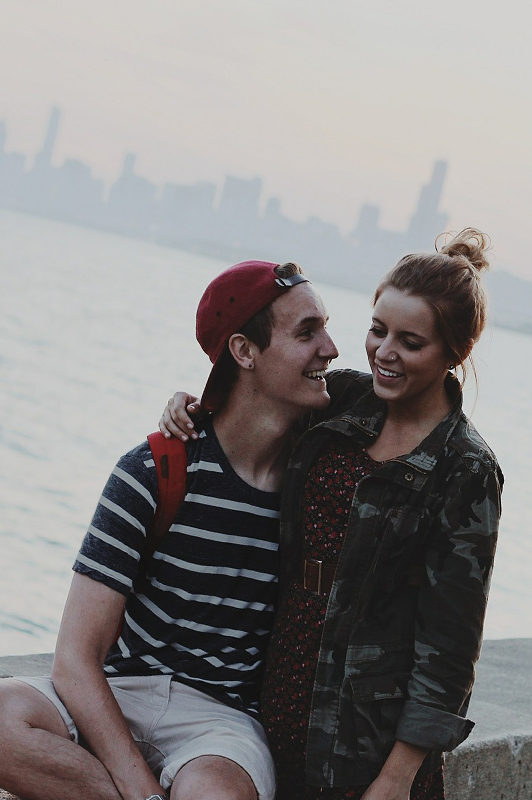 A couple laughing while sitting near a river.