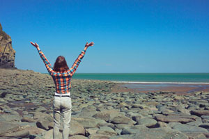 woman at beach with hands up