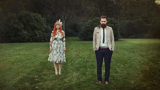 A hipster looking couple standing in the meadow,