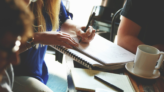 A woman writing something doen in her notebook.