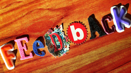 'Feedback' spelled out with different letters on a piece of wood.